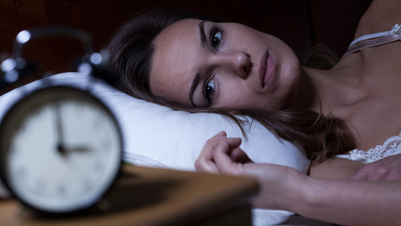 Woman with Insomnia Looking at Clock